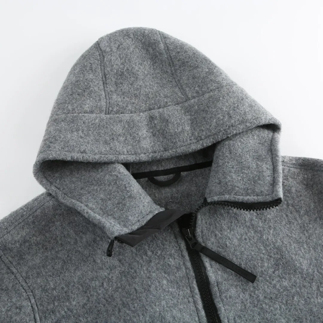 P780 Canada Goose Fleece Badge Hooded Jacket Fabric selection: Wool fleece fabric blended with wool as the main body and a very small amount of spandex and polyester fibers. Wool is a core natural ingredient that provides unparalleled temperature regulation, antibacterial and anti-odor properties and a skin-friendly feel. The feeding of a small amount of spandex gives the fabric a certain degree of four-way elasticity, making it non-restrictive during daily activities. As the basis of fleece's structure, polyester fiber enhances the fabric's durability, wrinkle resistance and quick-drying properties. It contributes to the loft of the fleece and provides functions such as trapping air.  Detail 1: The sleeves and hem are closed with 2×2 ribbing. Its strong elasticity can closely fit wrists and waists of different thicknesses, forming an effective 'seal' to prevent cold wind from blowing back. It can still maintain its original shape after repeated stretching and use, and is not easy to loose and deform. And the ribbed cuffs can convey a sense of design and enhance the visual beauty.  Detail 2: The combination of hood design and elastic buckle improves warmth and windproof performance when wearing.  Accessories: 1:1 customized elastic drawstring buckle, 1:1 customized zipper pendant, 1:1 customized armband SIZE: S M L XL